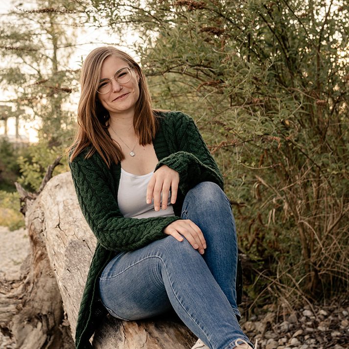 Teresa Knott in der Natur auf einem Baumstamm